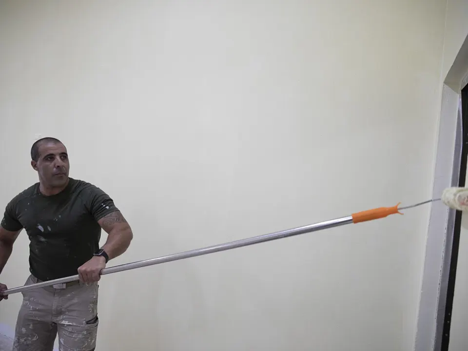 Painter rolling white paint onto an interior wall